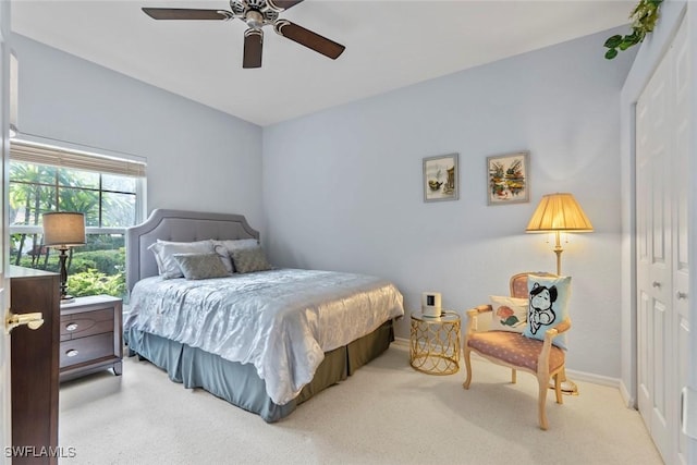 bedroom featuring light colored carpet, a closet, and ceiling fan