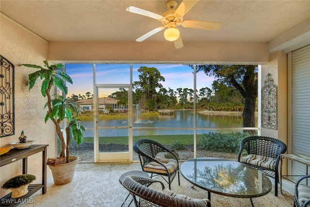 sunroom / solarium featuring a water view and ceiling fan