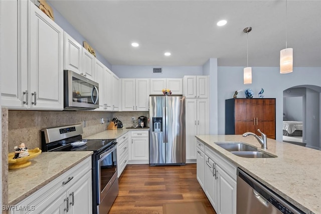 kitchen featuring appliances with stainless steel finishes, pendant lighting, tasteful backsplash, white cabinetry, and sink