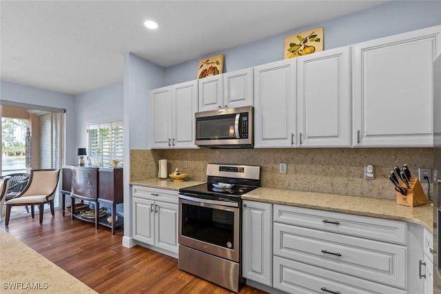 kitchen featuring tasteful backsplash, white cabinets, dark hardwood / wood-style flooring, stainless steel appliances, and light stone countertops