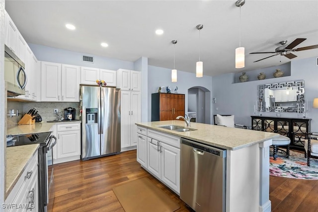 kitchen with white cabinetry, decorative backsplash, stainless steel appliances, and a center island with sink