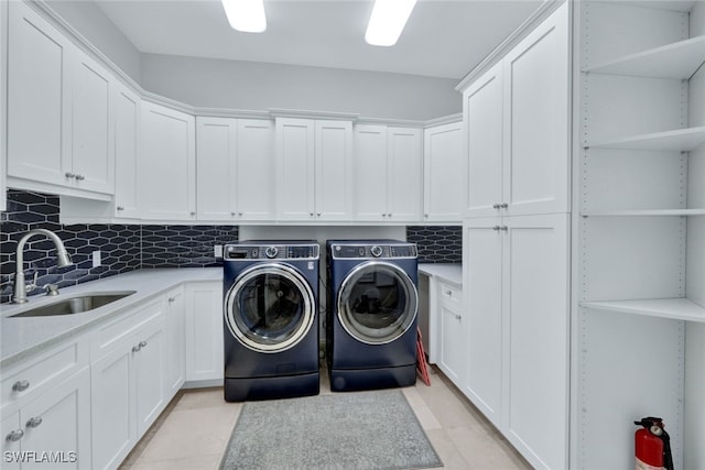 laundry room featuring independent washer and dryer, cabinets, sink, and light tile patterned floors