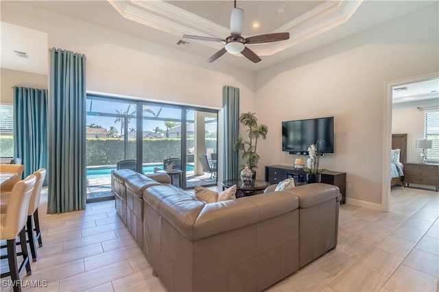 living room featuring crown molding, ceiling fan, and a tray ceiling