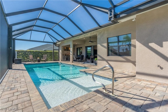 view of swimming pool with ceiling fan, a patio, and glass enclosure