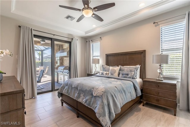 bedroom featuring a raised ceiling, access to exterior, ceiling fan, and multiple windows