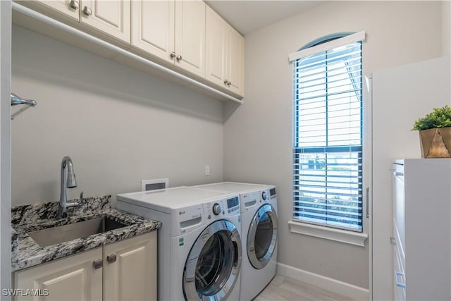 clothes washing area featuring cabinets, sink, and washing machine and dryer