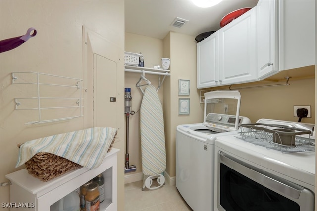 laundry area featuring light tile patterned floors, washing machine and dryer, and cabinets