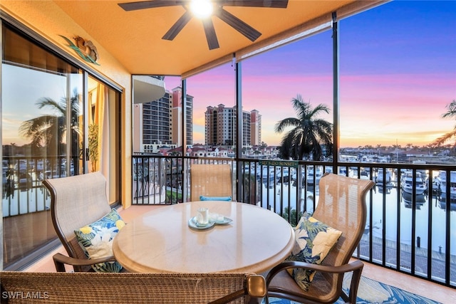 sunroom / solarium featuring ceiling fan and a water view