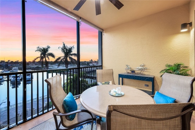 balcony at dusk featuring ceiling fan