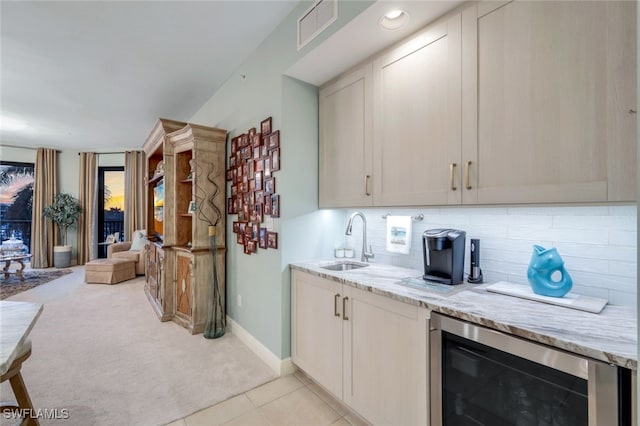 kitchen with sink, light tile patterned floors, wine cooler, light stone countertops, and decorative backsplash