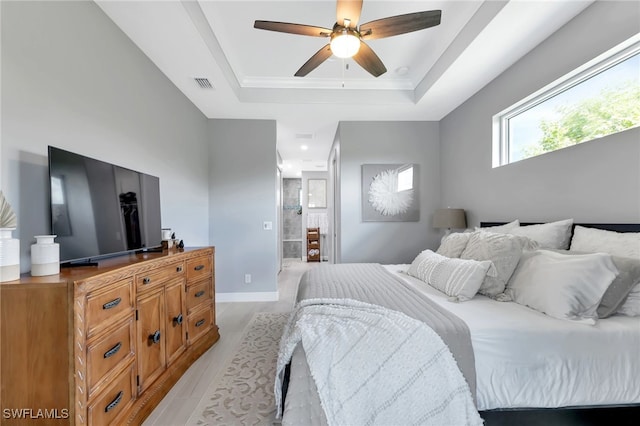 bedroom with light hardwood / wood-style floors, a raised ceiling, and ceiling fan