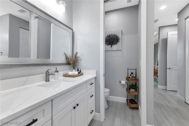 bathroom with vanity, toilet, and hardwood / wood-style floors