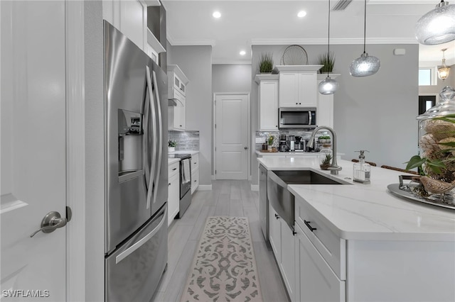 kitchen featuring appliances with stainless steel finishes, a kitchen island with sink, light stone countertops, white cabinets, and decorative light fixtures