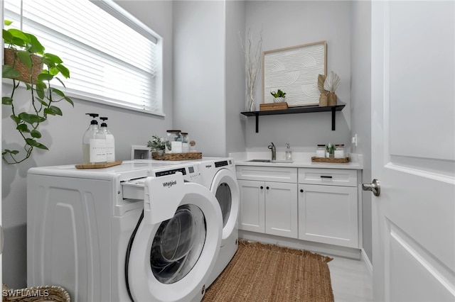 clothes washing area featuring cabinets, washer and dryer, and sink