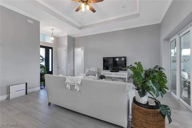 living room with a raised ceiling, crown molding, and ceiling fan