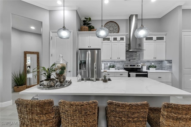 kitchen with appliances with stainless steel finishes, decorative light fixtures, backsplash, wall chimney range hood, and a center island with sink