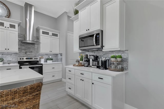 kitchen featuring white cabinetry, appliances with stainless steel finishes, wall chimney range hood, and backsplash