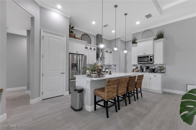 kitchen with pendant lighting, white cabinetry, a kitchen breakfast bar, a kitchen island with sink, and stainless steel appliances