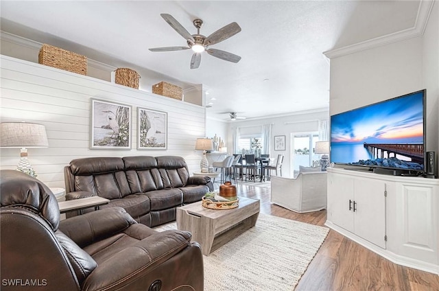 living room with a ceiling fan, crown molding, and light wood-style flooring