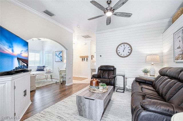 living area with visible vents, arched walkways, dark wood-style floors, ceiling fan, and crown molding