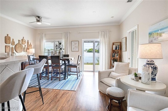 interior space with ceiling fan, ornamental molding, wood finished floors, and visible vents