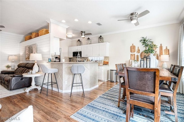 kitchen featuring light wood-style flooring, a kitchen bar, visible vents, and a ceiling fan