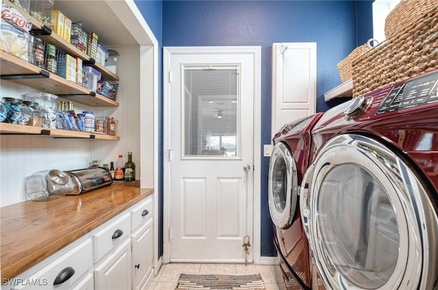 clothes washing area featuring light tile patterned floors, a dry bar, cabinet space, and washer and dryer