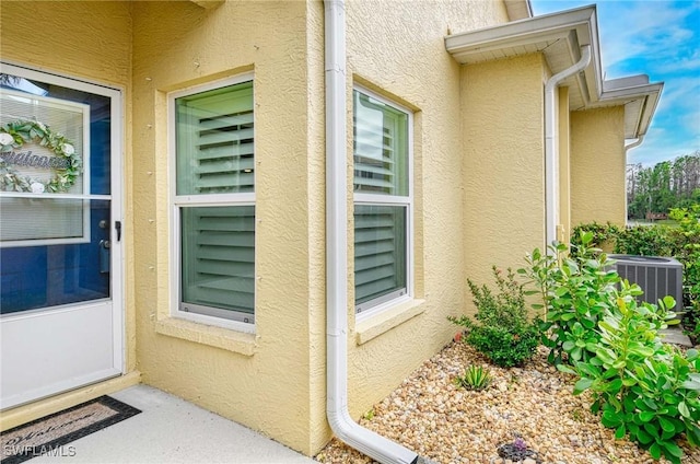 property entrance featuring central AC unit and stucco siding