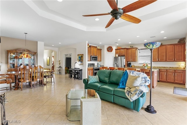 living room featuring ceiling fan, a raised ceiling, and light tile patterned floors