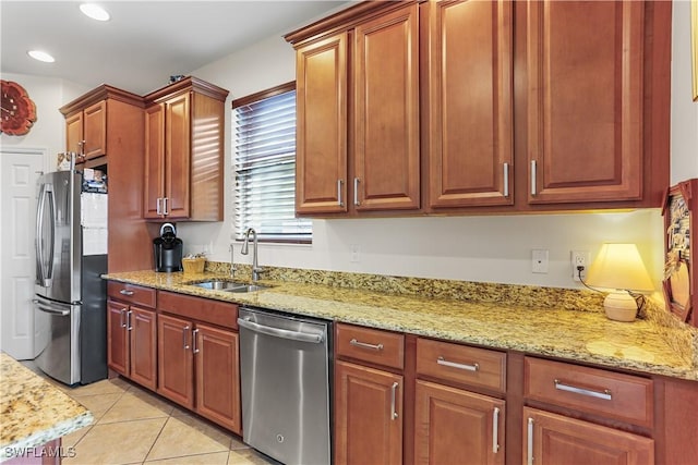 kitchen featuring appliances with stainless steel finishes, light stone countertops, sink, and light tile patterned floors