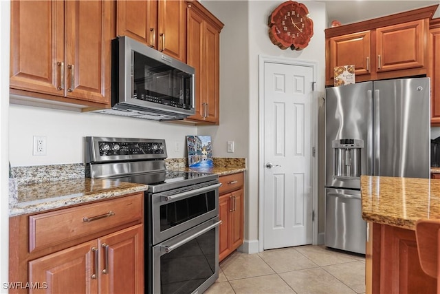 kitchen featuring appliances with stainless steel finishes, light tile patterned floors, and light stone counters