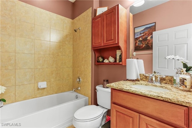 full bathroom featuring tiled shower / bath, vanity, and toilet