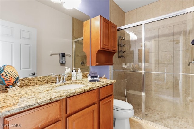 bathroom featuring tile patterned floors, toilet, a shower with door, and vanity