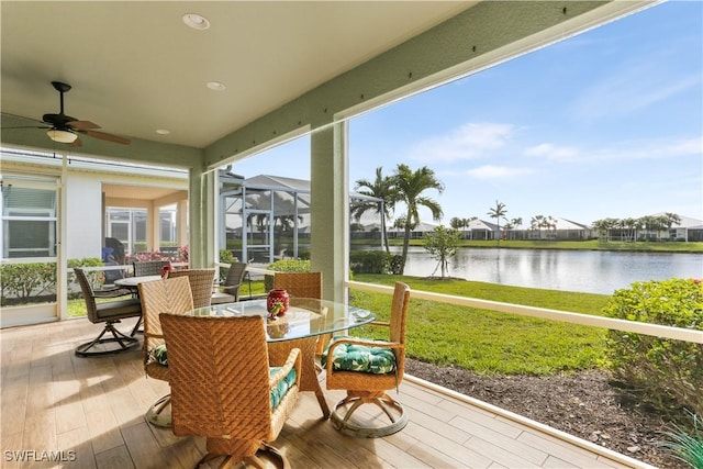 sunroom featuring a water view and ceiling fan