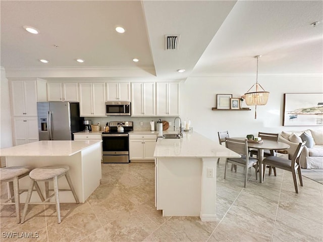 kitchen featuring sink, white cabinets, hanging light fixtures, ornamental molding, and stainless steel appliances