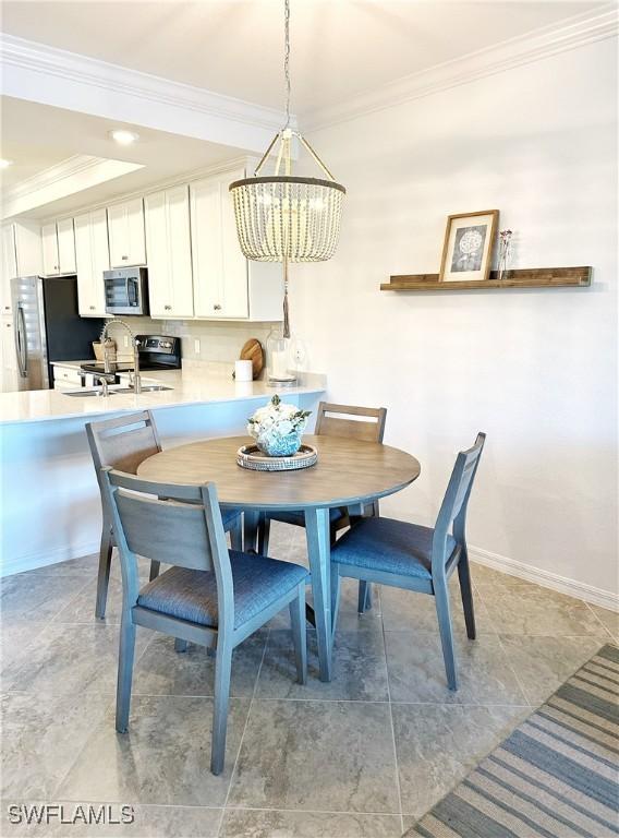 dining area featuring ornamental molding, a chandelier, and sink