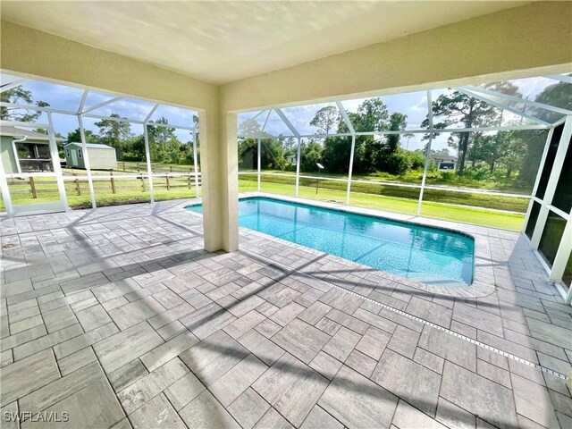 view of swimming pool featuring a lawn, a patio, and glass enclosure