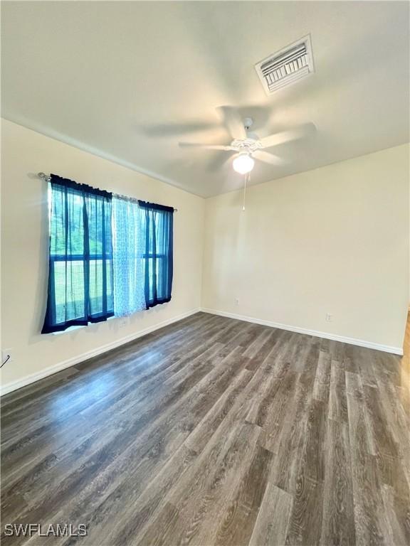 empty room featuring dark wood-type flooring and ceiling fan