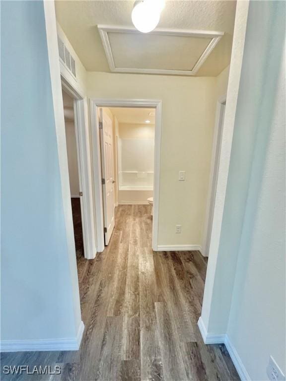 hall with wood-type flooring and a textured ceiling