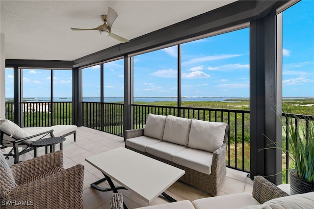 sunroom featuring a healthy amount of sunlight, ceiling fan, and a water view