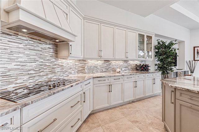 kitchen with white cabinetry, tasteful backsplash, light stone countertops, and custom exhaust hood