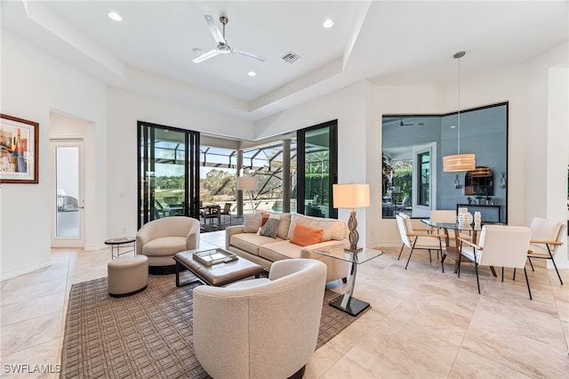 living room with ceiling fan and a tray ceiling