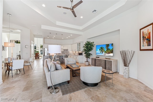 living room with a raised ceiling and ceiling fan