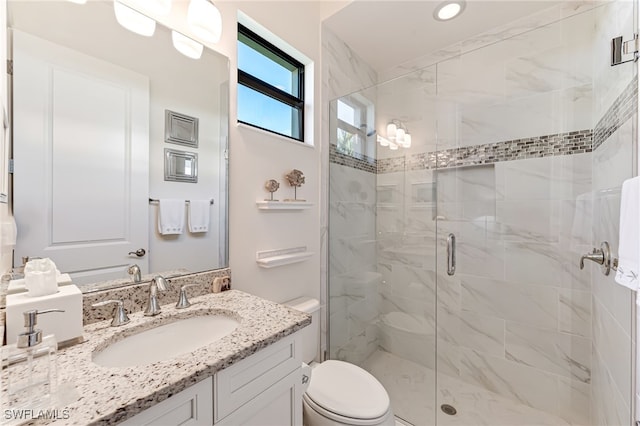 bathroom featuring a shower with door, vanity, and toilet