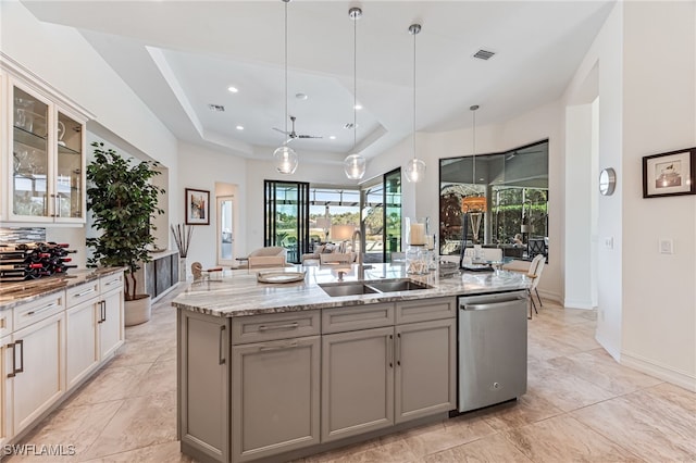 kitchen with sink, stainless steel dishwasher, gray cabinets, an island with sink, and pendant lighting