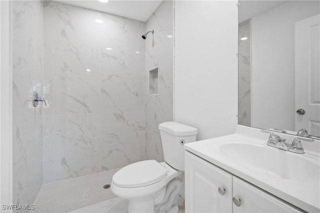 bathroom featuring vanity, toilet, and a tile shower