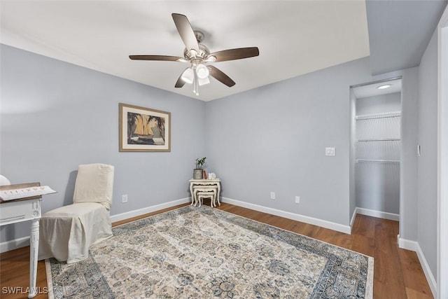 living area with dark wood-type flooring and ceiling fan