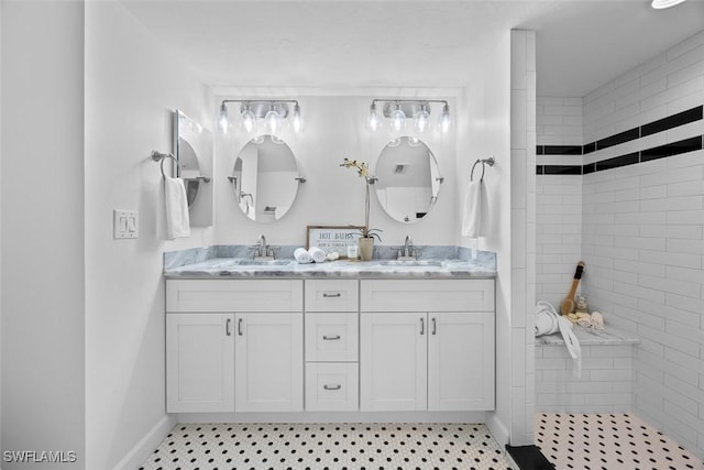 bathroom featuring tiled shower, vanity, and tile patterned flooring