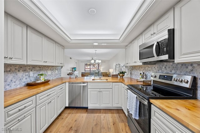 kitchen featuring white cabinetry, wood counters, appliances with stainless steel finishes, and kitchen peninsula