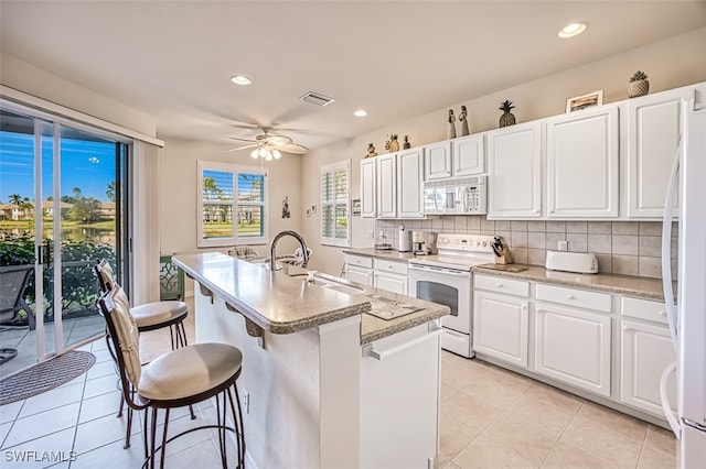 kitchen with white appliances, sink, an island with sink, and white cabinets